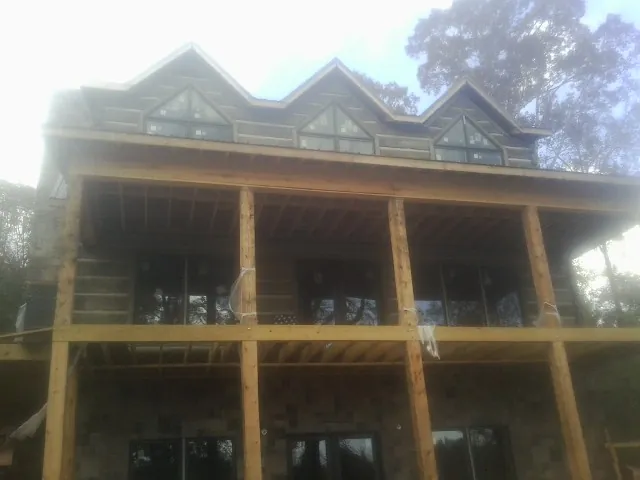 Dormers and porch framing on a large log home under construction — Roof Coating work by our crew in Saint Johns